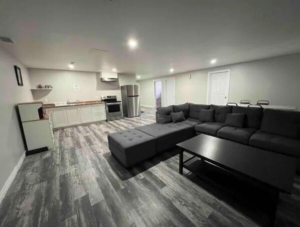 Relax in this open-plan living space with a sofa, ottoman, and coffee table, plus a fully equipped kitchen area.