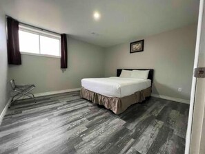 Simple, stylish room with a single bed, framed picture, and a small chair.