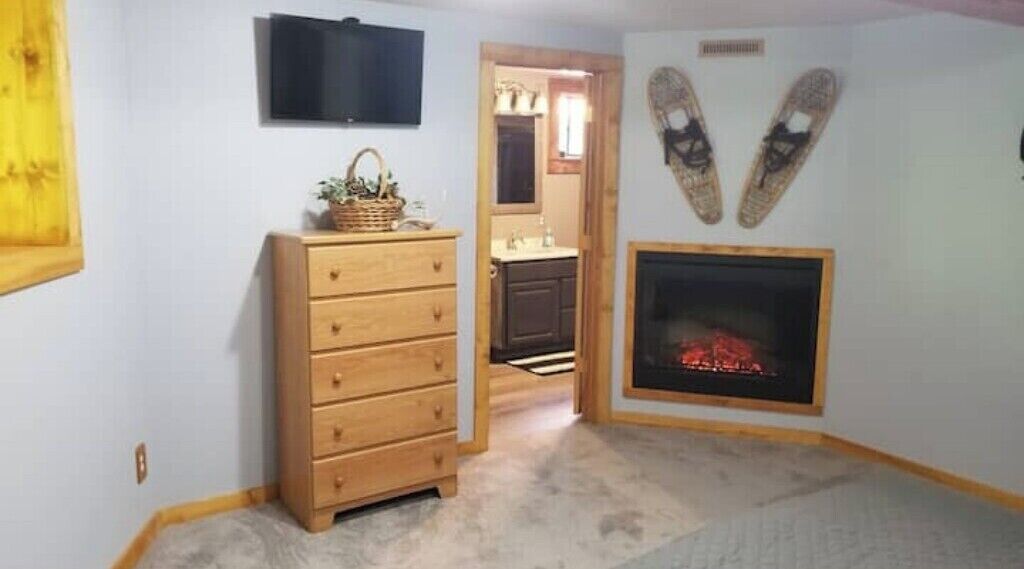 Una habitación con un aparador de madera, una chimenea y un televisor montado en la pared.
