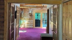 A log cabin interior with a purple carpet, wooden walls, and deer antlers mounted on the ceiling. - Wagonwheel Ranch (Viroqua)