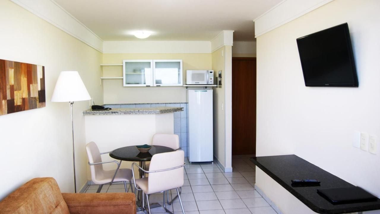 A compact kitchen with a microwave, refrigerator, and a flat-screen TV. There is a dining area with a table and chairs.