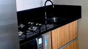 Cocina compacta con estufa integrada, microondas y encimera negra.