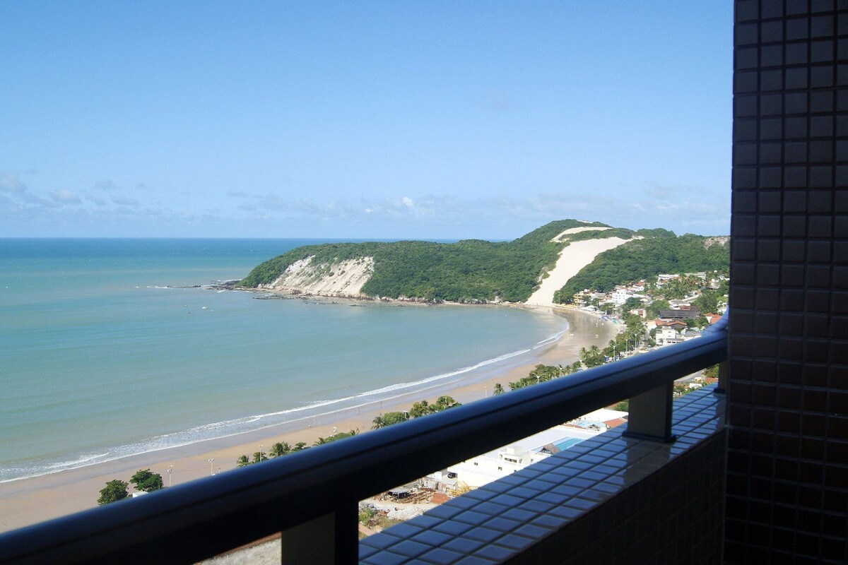 A coastal view with a beach, a cliff, and a residential area.
