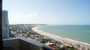 A coastal cityscape with a beach, buildings, and a clear sky. - CJC Short Stay Natal (Natal)