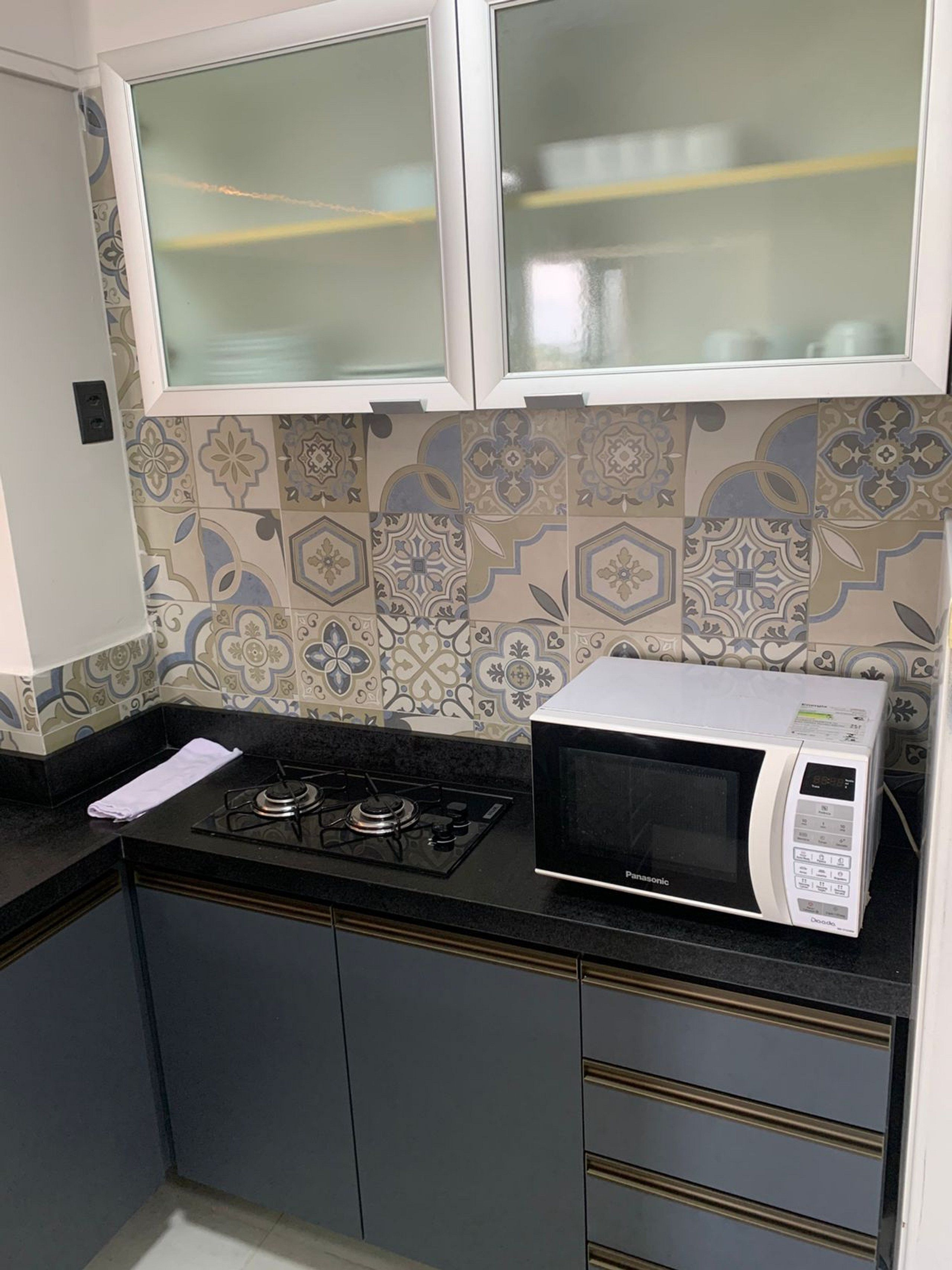 Une cuisine équipée d’une cuisinière à gaz, d’un four à micro-ondes, de carreaux décoratifs et de placards.