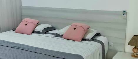 A neatly arranged bedroom with a bed, bedside tables, and a lamp.