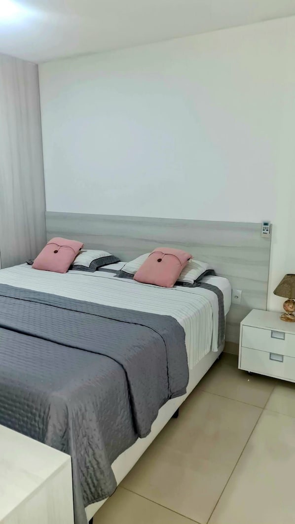 A neatly arranged bedroom with a bed, bedside tables, and a lamp. - CJC Short Stay Natal (Natal)