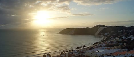 Un pueblo costero con una playa, edificios y una montaña al fondo.