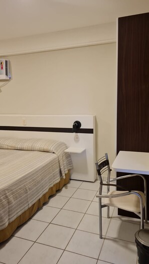 A bedroom with a bed, bedside table, chair, and a desk. - CJC Short Stay Natal (Natal)