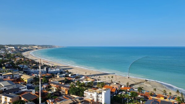 A coastal town with a beach, buildings, and clear skies. - CJC Short Stay Natal (Natal)