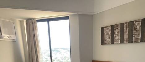 Una habitación de hotel con dos camas, una ventana con cortinas, aire acondicionado instalado en la pared y una lámpara.