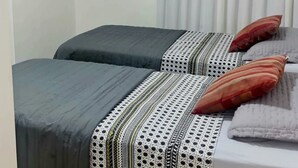 Ein Zimmer mit zwei Betten, einem fensterbelaubten Fenster und einer Klimaanlage.