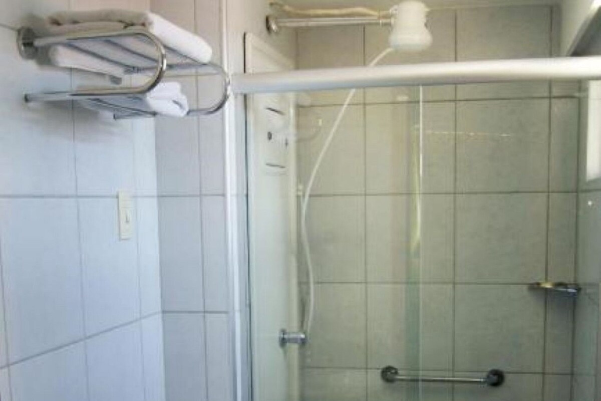 A bathroom with a glass-enclosed shower, a toilet, and a sink with a towel.