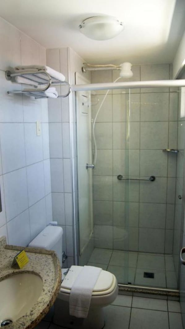 A bathroom with a glass-enclosed shower, a toilet, and a sink with a towel. - CJC Short Stay Natal (Natal)