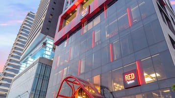 A modern building with a prominent 'RED' sign, large glass windows, and a unique red structure in front.