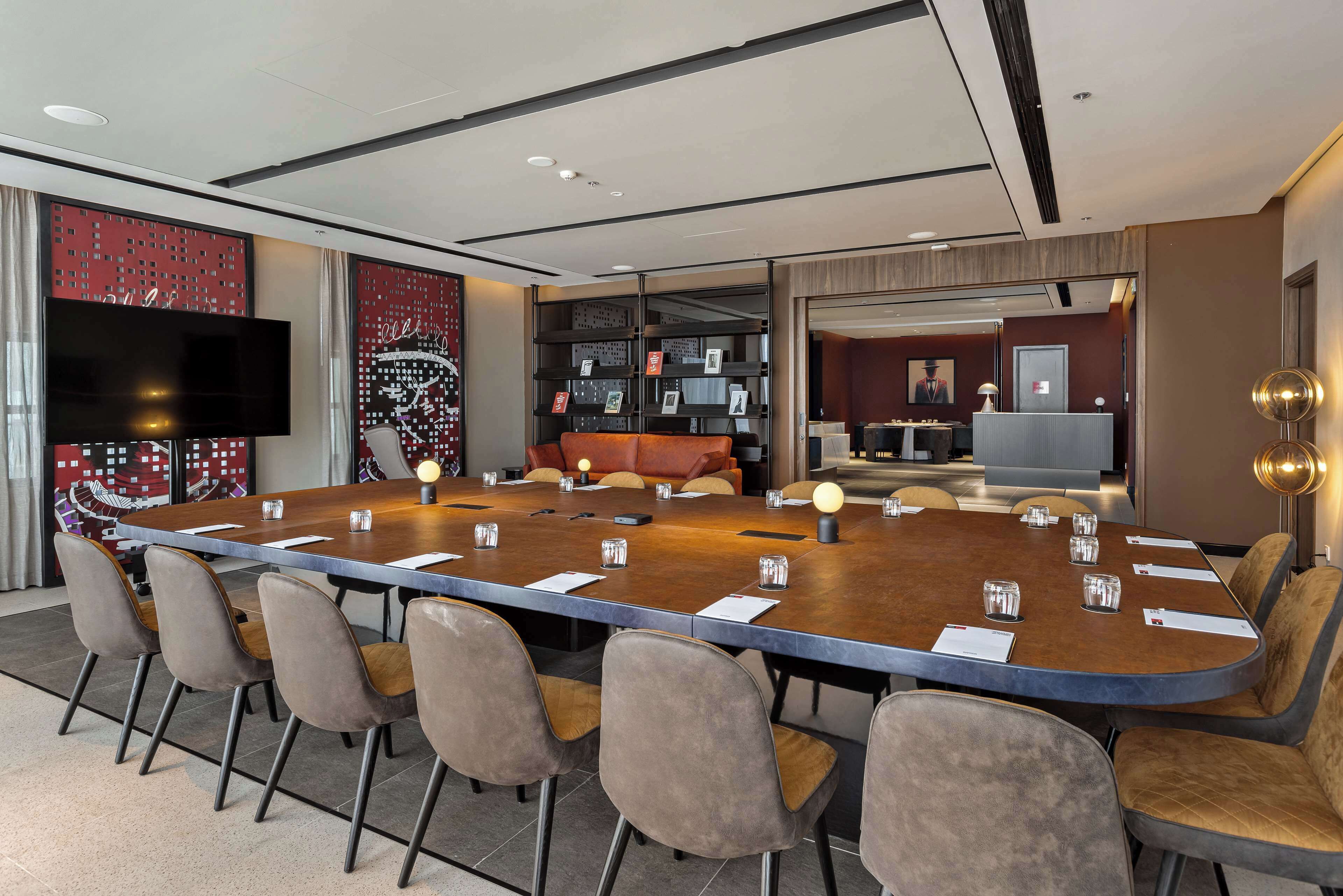 A conference room with a long table, multiple chairs, a television, and a reception desk.