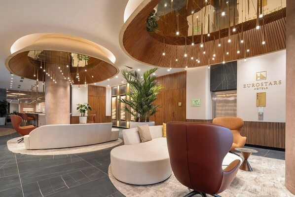 A modern hotel lobby with a curved reception desk, comfortable seating areas, and a prominent Eurostars Hotels sign.