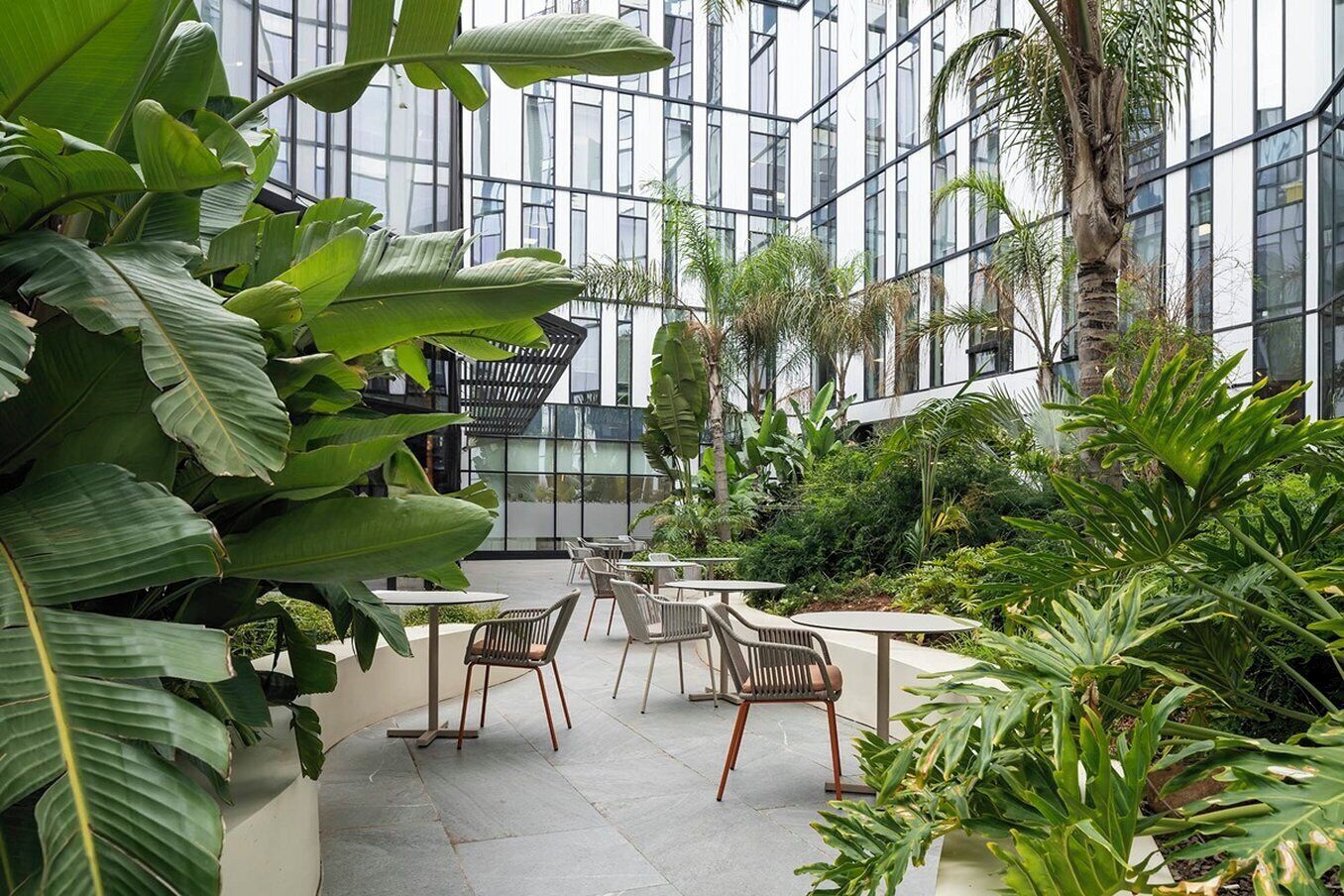 An indoor garden with seating areas and a modern building in the background.