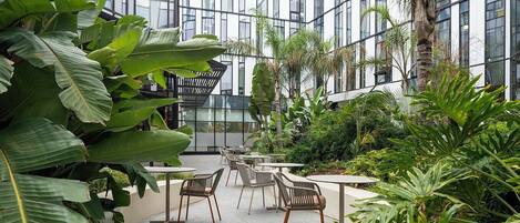 An indoor garden with seating areas and a modern building in the background.
