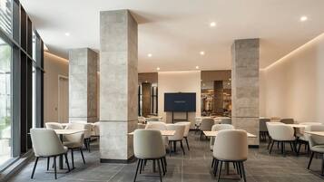 Un restaurant moderne avec de hauts plafonds, de grandes colonnes et un téléviseur à écran plat fixé au mur.
