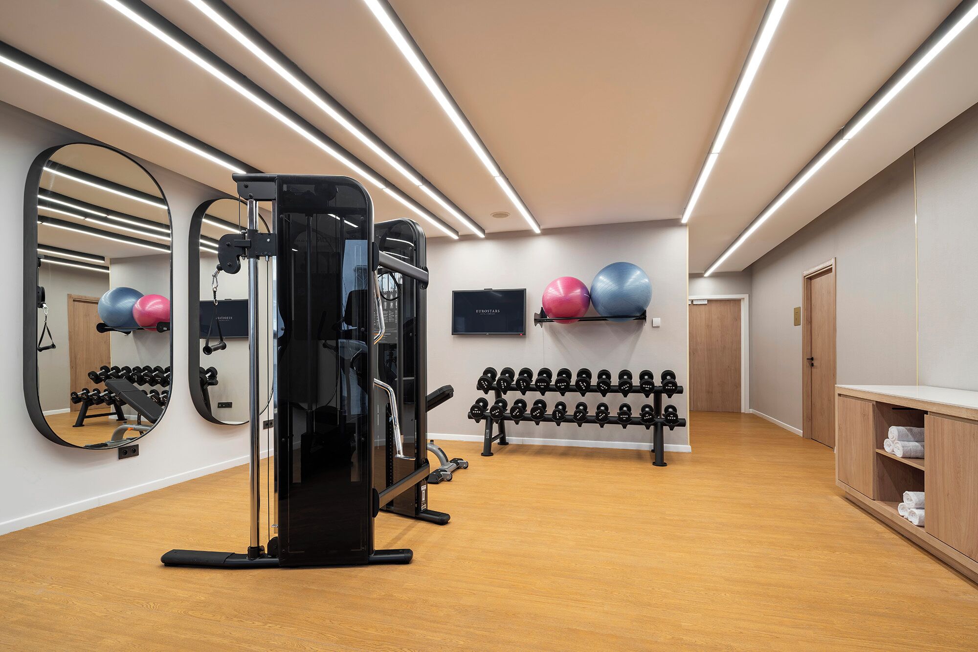 A gym with exercise equipment, a mirror, and a television.