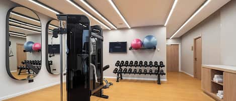 A gym with exercise equipment, a mirror, and a television.