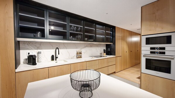 Een moderne keuken met houten kastjes, een marmeren aanrechtblad en ingebouwde apparatuur.