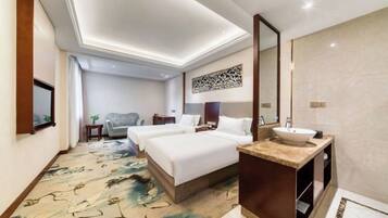 A hotel room with two beds, a bathroom with a sink, and a large mirror.
