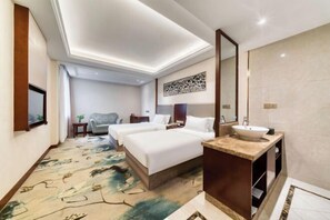 Ein Hotelzimmer mit zwei Betten, einem Badezimmer inklusive Waschbecken und einem großen Spiegel.