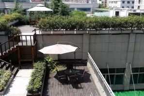 Eine Dachterrasse mit Tisch und Stühlen, eine Treppe und Blick auf die Stadt.