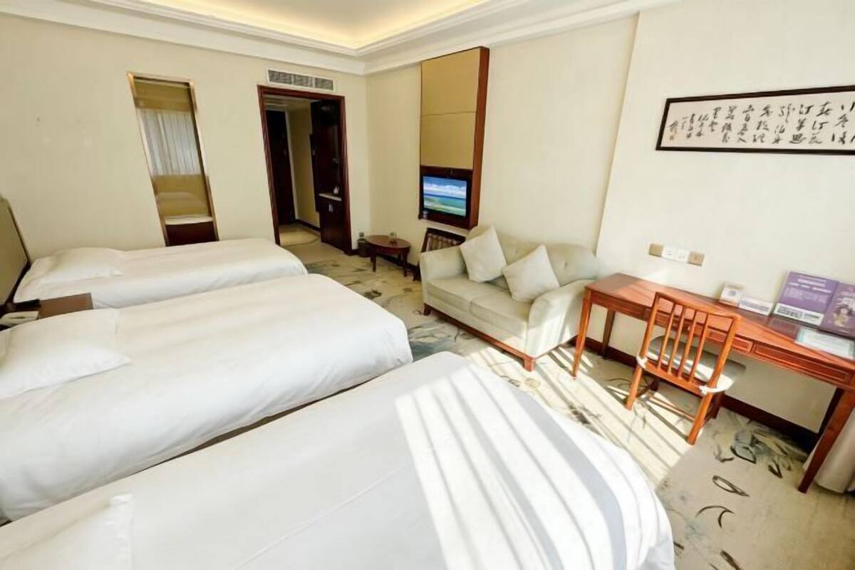 Une chambre d’hôtel avec deux lits, un canapé, un bureau et une télévision.