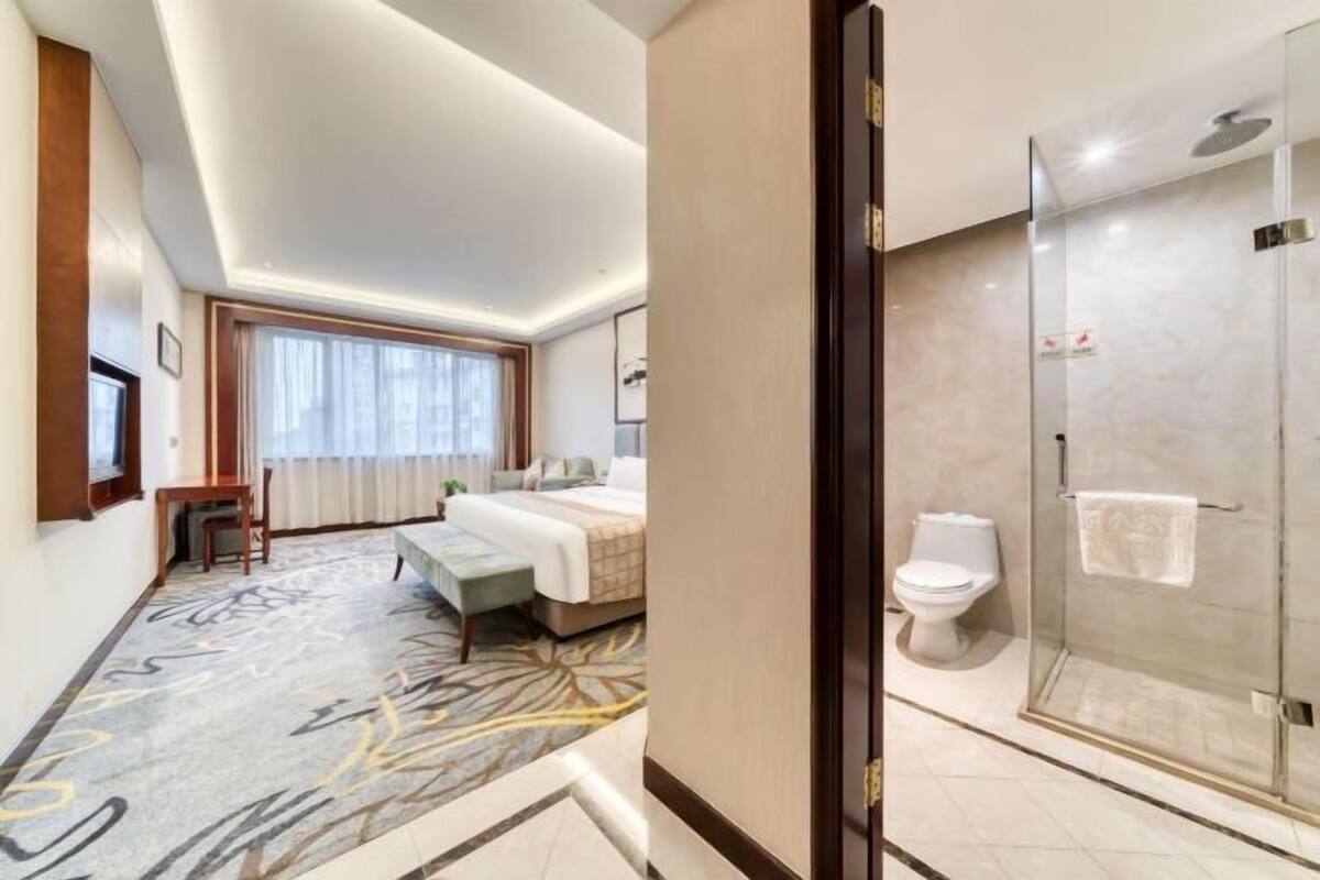 Une chambre d’hôtel comprenant un lit, une table de chevet et un espace douche.