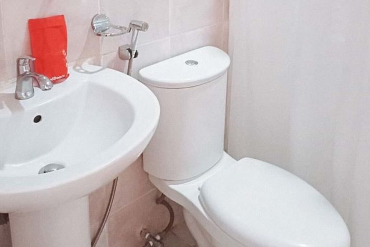 Un baño con lavamanos blanco, inodoro y felpudo rojo.