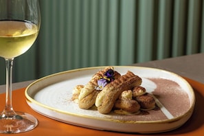 A plate of dessert with a glass of white wine on a table. - Courtyard Milano Linate (Milan)