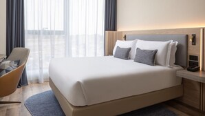 Une chambre d’hôtel avec un grand lit, une table de chevet avec un téléphone et une chaise.
