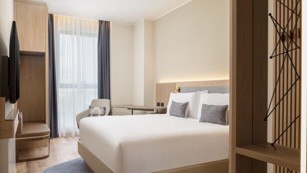 Une chambre d’hôtel avec un grand lit, un bureau, une chaise et un téléviseur.