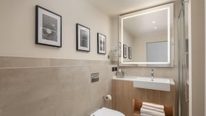 Une salle de bain moderne avec des toilettes, un lavabo et un grand miroir.