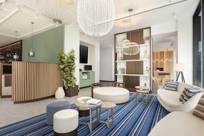 A modern hotel lobby with a reception desk, seating area, and a bar. - Courtyard Milano Linate (Milan)