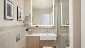 Une salle de bain moderne avec un grand miroir, un lavabo et une douche à parois de verre.
