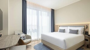 A modern hotel room with a large bed, a desk, and a chair. - Courtyard Milano Linate (Milan)