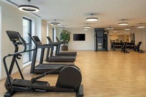 A gym with treadmills, a weight bench, and a TV screen. - Courtyard Milano Linate (Milan)