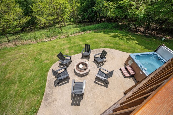 An outdoor patio with a fire pit, seating, and a hot tub.