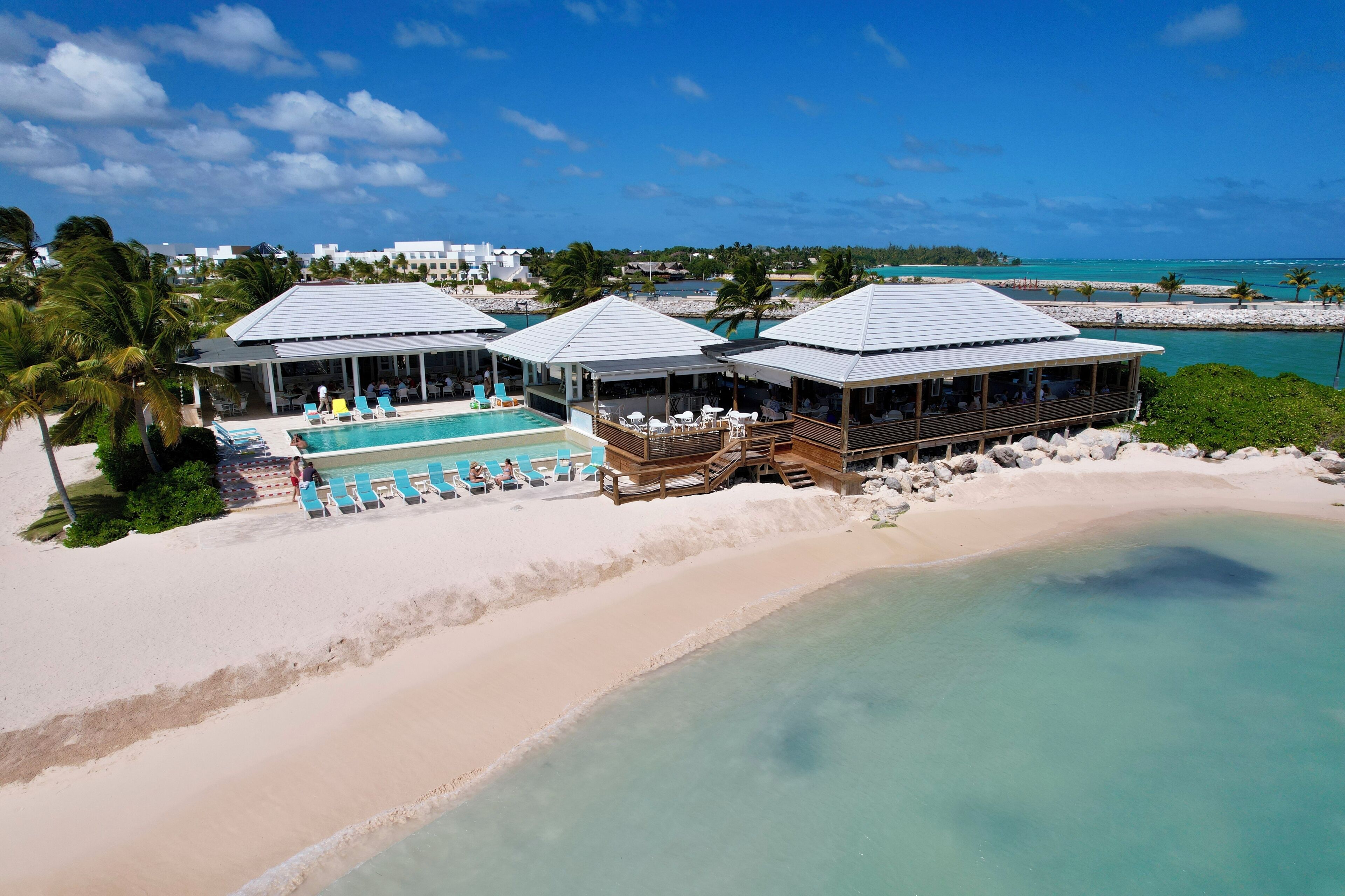 A beachfront resort with multiple overwater bungalows, a pool area, and a sandy beach.