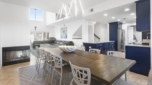 A modern kitchen with a wooden dining table, white chairs, and a blue accent wall. - Portside Villas Unit 6 (Pensacola Beach)
