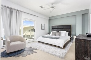 Ein Schlafzimmer mit einem Bett, einem Sessel, einem Schreibtisch und einem Balkon.