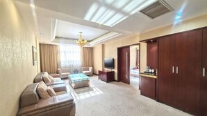 A hotel room with a sofa set, a coffee table, a TV, a wardrobe, and a minibar. - Yunshuijian Hotel (Jiaozuo)