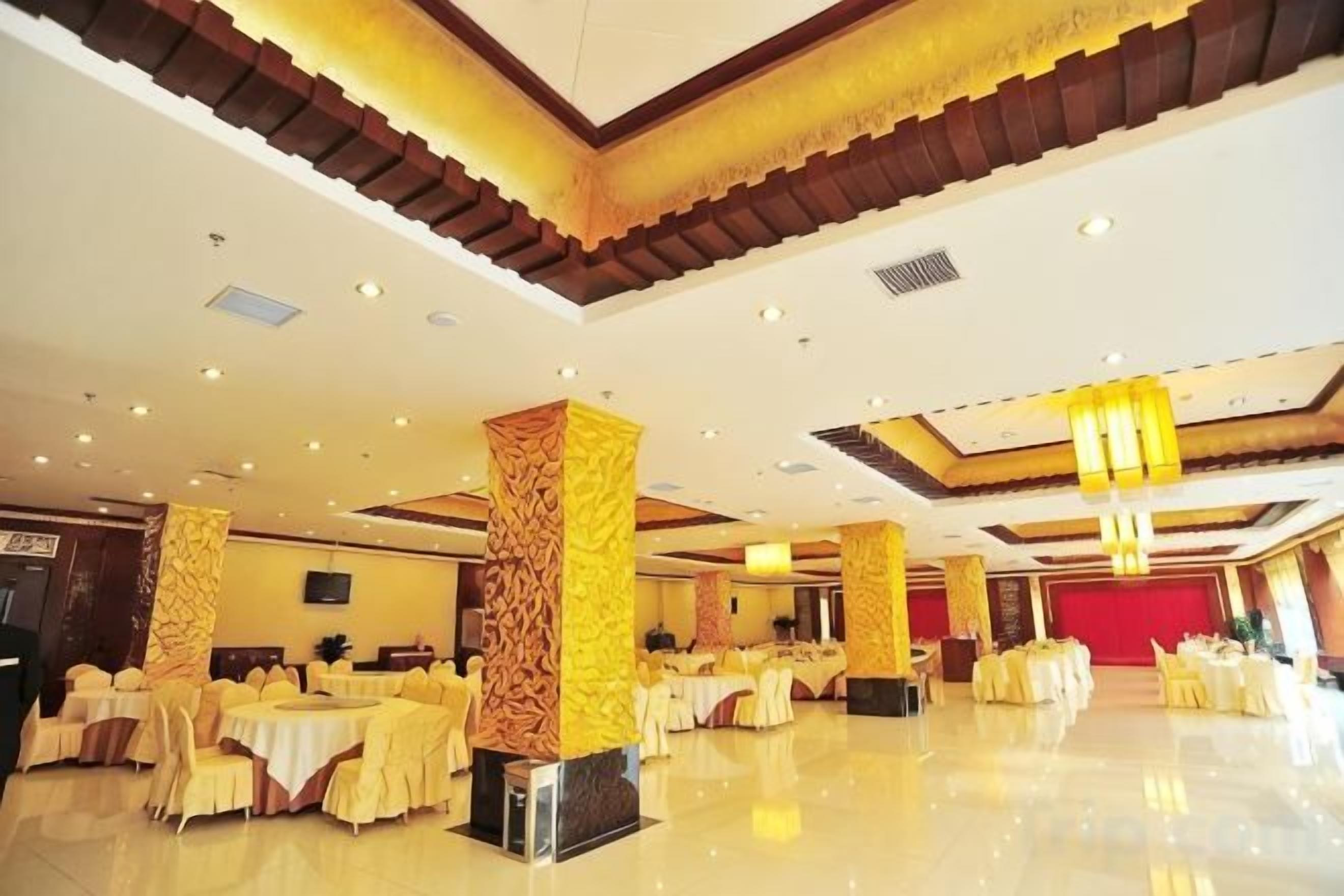 A spacious banquet hall with high ceilings, chandeliers, and round tables set for events.