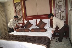 Une chambre d’hôtel avec un grand lit, une tête de lit ornée d’un panneau décoratif et une table de chevet avec une lampe.