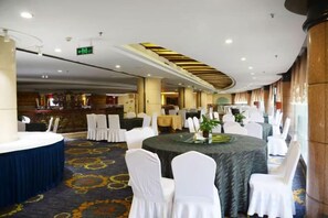 A banquet hall with round tables, white chairs, and a carpeted floor. - Yunshuijian Hotel (Jiaozuo)