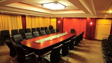 A conference room with a long table, multiple chairs, and a projector screen.